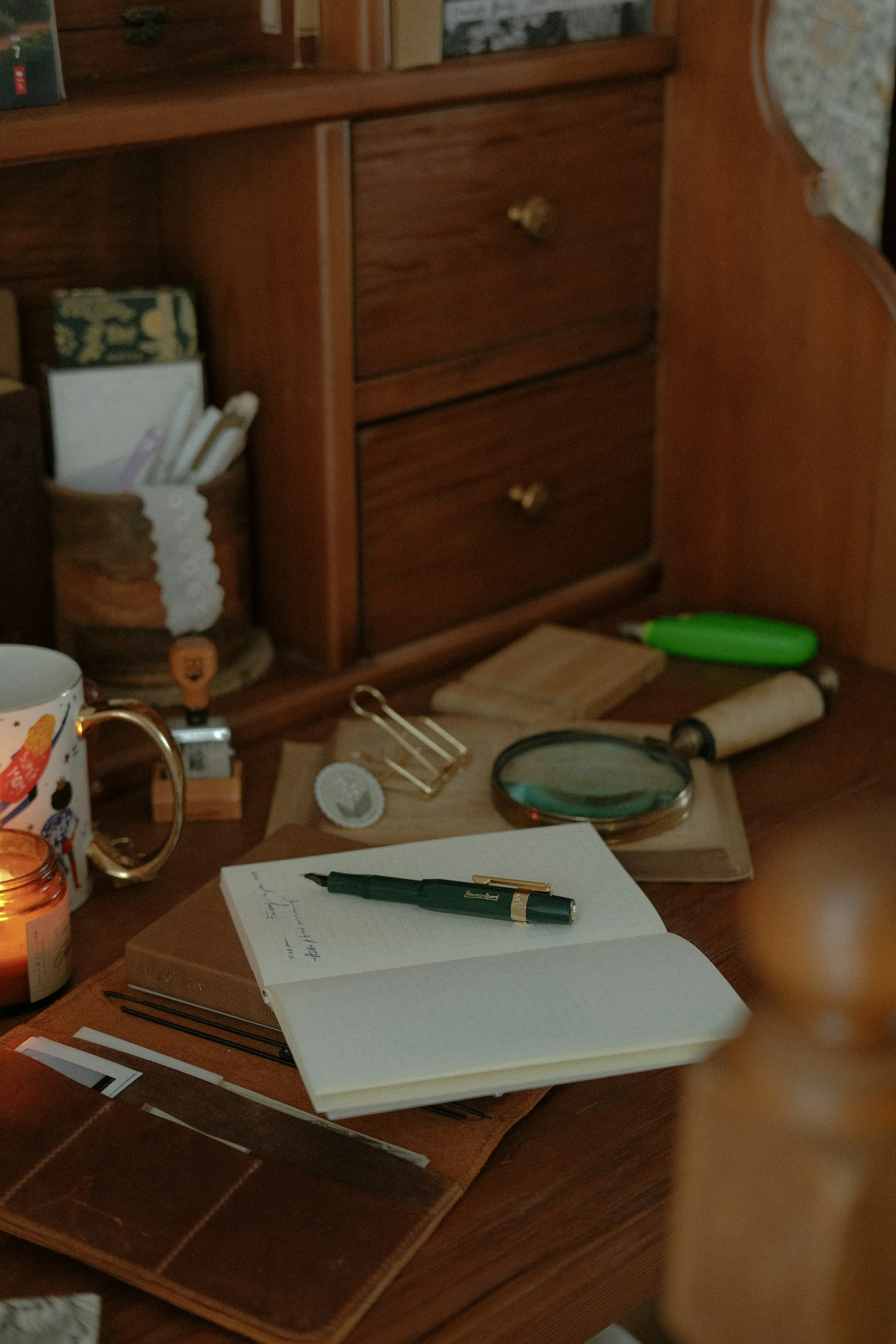 A notebook, pen and magnifying glass on a desk